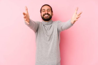 Pembe arka planda izole edilmiş genç, uzun saçlı adam kameraya sarıldığı için kendinden emin hissediyor..