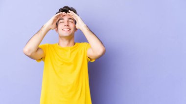 Mor arka planda izole edilmiş genç beyaz adam, mutlu bir şekilde ellerini başının üstünde tutarak gülüyor. Mutluluk kavramı.