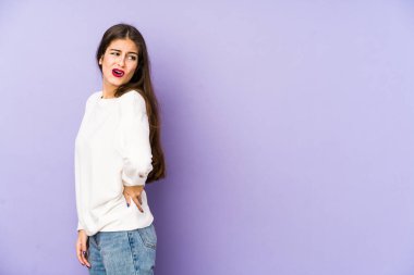 Mor arka planda izole edilmiş beyaz bir kadın sırt ağrısı çekiyor..