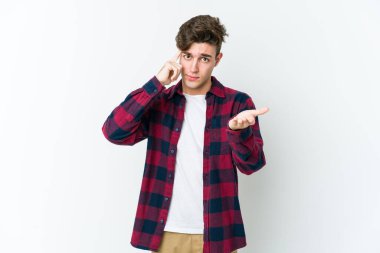 Beyaz arka planda izole edilmiş genç beyaz bir adam elinde bir ürün tutuyor ve.