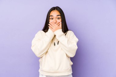 Mor arka planda izole edilmiş genç bir kadın elleriyle ağzını kapatırken şok oldu..