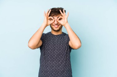 Mavi bir arka planda izole edilmiş genç bir Arap gözlerinde sorun olmadığını gösteriyor.