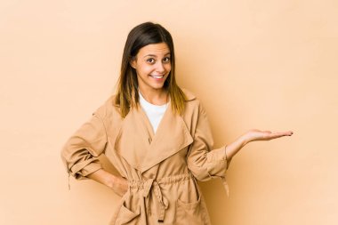 Bej arka planda izole edilmiş genç bir kadın bir avuç içinde fotokopi alanı ve belinde bir el daha olduğunu gösteriyor..