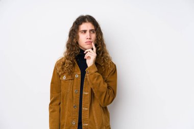 Uzun saçlı adam şüpheli ve şüpheci ifadesiyle yanlamasına poz veriyor..