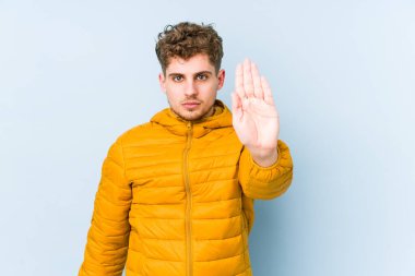 Sarışın, kıvırcık saçlı, beyaz tenli bir adam elini uzatmış, dur işareti göstererek seni engelliyor..