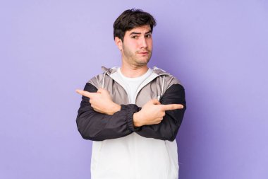 Mor arka plan noktalarından izole edilmiş genç adam iki seçenek arasında seçim yapmaya çalışıyor..