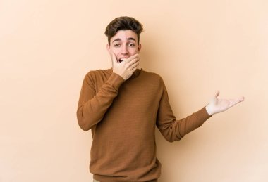 Beyazların arka planında izole edilmiş genç beyaz bir adam bir avuç içinde fotokopi alanı tutuyor, el üstünde tutuyor. Şaşırmış ve mutlu..