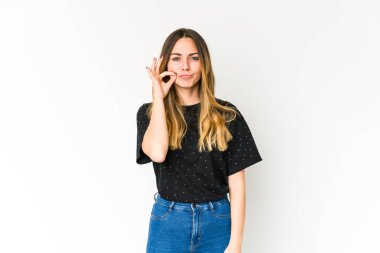 Beyaz arka planda izole edilmiş beyaz tenli genç bir kadın parmakları dudaklarında bir sır saklıyor..