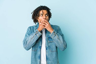 Kot ceket giyen genç siyahi bir adam. Fotokopi odasına dikkatlice bakıyor. Ağzını eliyle kapatıyor..