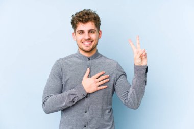 Sarışın, kıvırcık saçlı, beyaz tenli bir adam tek başına yemin ediyor ve elini göğsüne koyuyor..