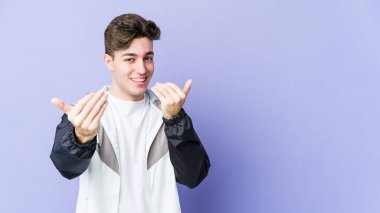 Mor arka planda izole edilmiş genç beyaz adam sanki seni davet ediyormuş gibi seni işaret ediyor..