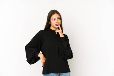 Beyaz arka planda soyutlanmış beyaz tenli genç bir kadın şüpheli ve şüpheci bir ifadeyle yana bakıyor..