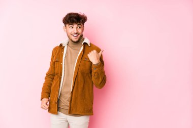 Pembe arka planda yalnız poz veren genç bir Arap. 