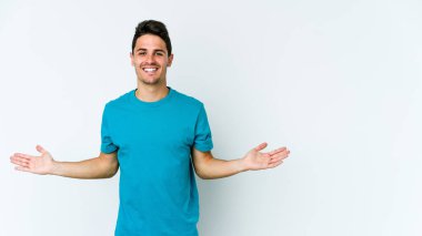 Beyaz arka planda izole genç beyaz adam kollarıyla ölçek yapar, mutlu ve kendinden emin hisseder..