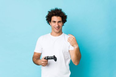 Kafkasyalı kıvırcık bir adam elinde oyun kumandasıyla seni işaret ediyor sanki davet ediyormuş gibi..