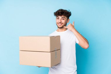 Genç Arap adam, izole edilmiş kutular tutuyor. Parmaklarıyla bir cep telefonu hareketi gösteriyor..