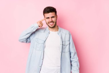 Beyaz arka planda poz veren beyaz tenli genç bir iş adamı işaret parmağıyla hayal kırıklığı jesti yapıyor.