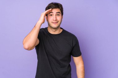 Mor arka planda izole genç adam yüksek sesle bağırıyor, gözleri açık ve elleri gergin tutuyor..