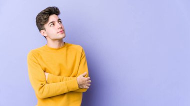 Mor arka planda izole edilmiş genç beyaz adam hedeflere ve amaçlara ulaşmayı hayal ediyor.