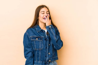 Beyaz tenli genç bir kadın bej arka planda izole edilmiş gülerek, kaygısız, doğal duygularla gülüyor..