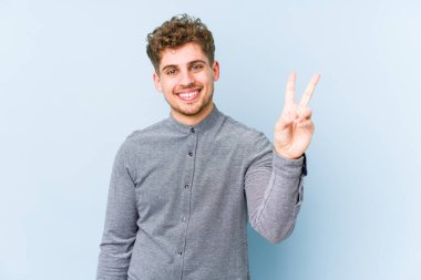 Sarışın, kıvırcık saçlı, beyaz, neşeli ve tasasız bir adam parmaklarıyla barış sembolü gösteriyor..