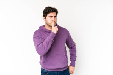 Genç adam beyaz arka planda izole edilmiş bir şekilde ya sır saklıyor ya da sessizlik istiyor..