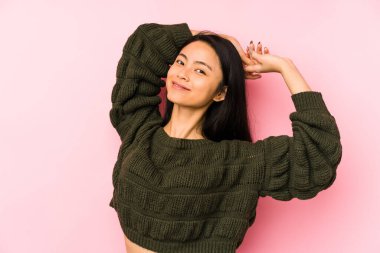 Pembe arka planda izole edilmiş genç Çinli kadın kollarını uzatıyor, rahat bir konumda..