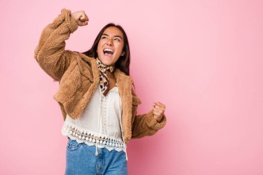 Genç melez Hintli kadın kısa bir koyun derisi giyiyor zaferden sonra yumruk kaldırıyor, kazanan konsept..