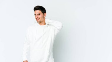 Beyaz arka planda izole edilmiş genç beyaz bir adam kafasının arkasına dokunuyor, düşünüyor ve bir seçim yapıyor..