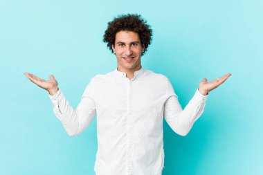 Zarif bir gömlek giyen genç, kıvırcık, olgun bir adam kollarıyla terazi yapar, mutlu ve kendinden emin hisseder..