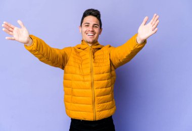 Mor arka planda izole genç beyaz adam kameraya sarıldığı için kendinden emin hissediyor..