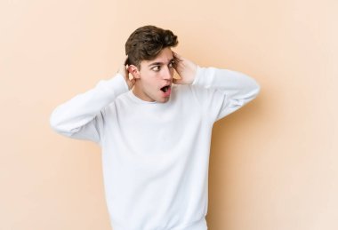 Beyaz tenli genç adam bej arka planda izole edilmiş bağırıyor, çok heyecanlı, tutkulu, bir şeyden memnun..