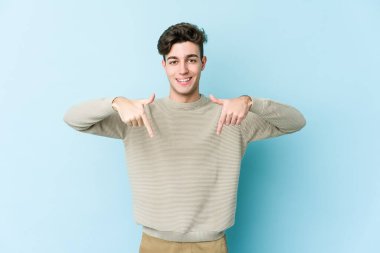 Kafkasyalı genç adam mavi arka planda izole edildi. Parmakları aşağıda, olumlu bir his var..