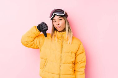 Pembe arka planda kayak kıyafetleri giyen genç beyaz bir kadın hoş olmayan bir jest gösteriyor. Anlaşmazlık konsepti.