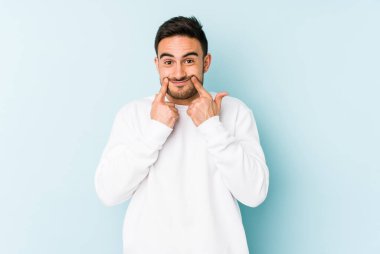 Kafkasyalı genç adam mavi arka planda izole edilmiş iki seçenek arasında şüphe duyuyor.