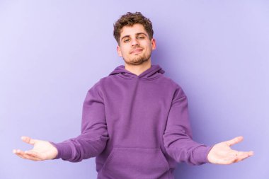 Sarışın, kıvırcık saçlı, beyaz tenli bir adam. Hoş bir yüz ifadesi sergiliyor..