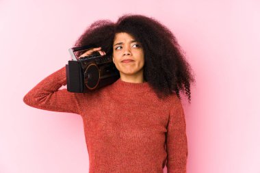 Elinde kaset tutan genç bir afro kadın kafası karışmış, kendinden emin değil..