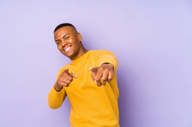 Mor arka planda izole edilmiş genç latin adam öne bakan neşeli gülümsemeler.