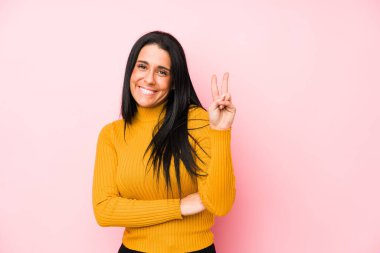 Pembe arka planda izole edilmiş beyaz bir kadın iki numarayı parmaklarıyla gösteriyor..