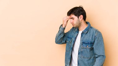 Bej arka planda izole edilmiş genç bir adam. Başı ağrıyor, yüzüne dokunuyor..