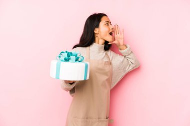 Elinde pasta tutan genç Çinli kadın neşeli ve kendinden emin bir şekilde iyi bir jest yapıyor..