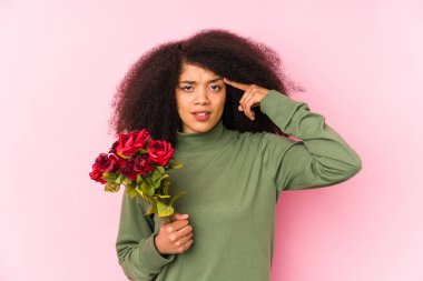 Elinde gül tutan genç bir afro kadın. Elinde gül tutan genç bir afro kadın. İşaret parmağıyla hayal kırıklığı jesti yapıyor..