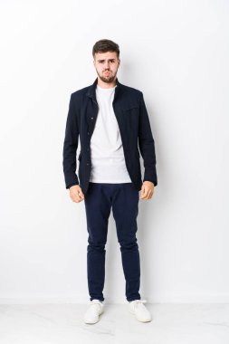 Tam vücut Kafkasyalı genç adam izole olmuş yanakları patlatıyor, yorgun bir ifadesi var. Yüz ifadesi kavramı.