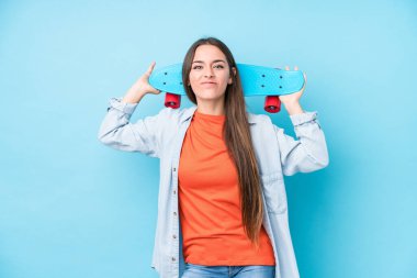 Genç beyaz kaykaycı kadın mavi arka planda izole edilmiş.