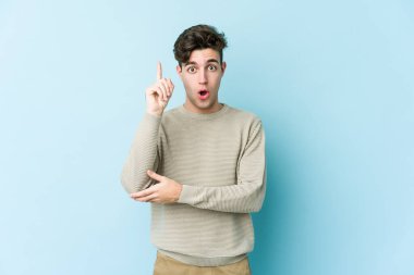 Kafkasyalı genç adam mavi arka planda izole edildi. Harika bir fikri var, yaratıcılık kavramı..