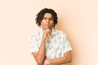 Genç Afrikalı Amerikalı Rasta adam şüpheli ve şüpheci bir ifadeyle yana bakıyor..