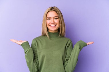 Sarışın, yalnız, beyaz bir kadın kollarıyla ölçeği yapıyor, mutlu ve kendinden emin..