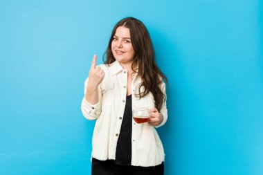 Genç, kıvrımlı bir kadın elinde çay fincanıyla seni işaret ediyor sanki davet ediyormuş gibi..