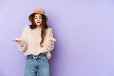 Mor arka planda izole edilmiş beyaz bir kadın avuçlarıyla bir şey tutuyor ve kameraya sunuyor..