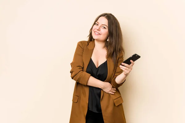 Young curvy woman holding a phone laughing and having fun.